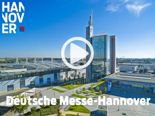 Luftaufnahme der Deutschen Messe Hannover mit Glasb&uuml;rogeb&auml;ude, Funkturm und Messehallen mit markanter Dachkonstruktion.
